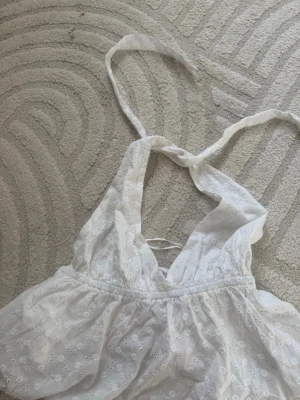 Vit broderad halterneck topp från Gina Tricot - Supersöt vit halterneck topp från Gina Tricot med broderade blommor och knyt i nacken. Aldrig använd i storlek S🤍🥰