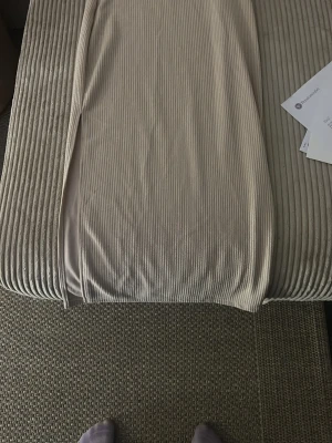 Beige ribbad långkjol med slits - Säljer en beige långkjol med ribbad struktur och slits på sidan. Kjolen har en mjuk och stretchig känsla, perfekt för en avslappnad men ändå stilren look. Passar till många olika outfits och är enkel att matcha.