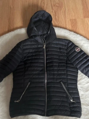 Marinblå dunjacka med huva från Colmar - Storlek 48 och passar mig som har S jätte bra! Skriv om ni vill ha äktighetsbevis, Snygg svart dunjacka från colmar. Jackan är perfekt för kalla vinterdagar. Klassisk passform och lätt vaddering, hållt mig varm under vintern. PRIS KAN DISKUTERAS!! En liten defekt att de är ett ytte litet hål vid ena ärmen, kommer inte ur något dun och kan lagas så de inte syns med tejp eller sy det! De är så litet så man knappt ser det! Därav priset/ NYPRIS 3500, säljer pgr av att ja behöver pengar