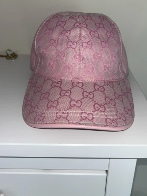 Rosa keps med monogram  - Säljer en snygg rosa keps  med det klassiska monogramet i hela tyget. Kepsen har böjd skärm och är tillverkad i ett canvasliknande material. Perfekt för dig som vill ha en trendig accessoar med lyxig känsla.