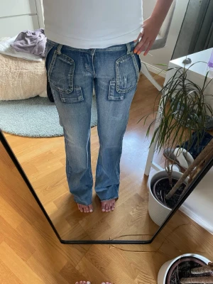 Blå jeans med stora fickor - Säljer ett par blå boutcut jeans och stora, markerade fickor både fram och bak. Jeansen har en cool vintagekänsla och detaljerade sömmar. Perfekta för dig som gillar en avslappnad och trendig stil. Står ingen storlek med tror xs jag är 166 lång
