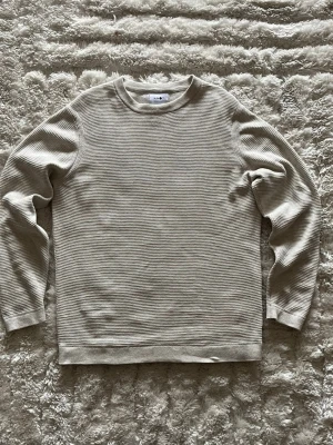 NN07 Julian stickad tröja i beige - stl M - NN07 Julian stickad tröja i beige, storlek M. 100% bomull, strukturstickad med rund hals och ribbade muddar.  Använd men i mycket fint skick, inga hål eller fläckar. Personen på bilden är 189cm, väger 78kg.  Rök- och djurfritt hem. Skriv gärna om du vill ha fler bilder eller undrar något!