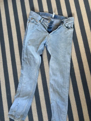 Ljusblå raka jeans från weekday sunday - Säljer ett par ljusblå jeans med rak passform och klassisk femficksdesign. Jeansen har normal midja och är tillverkade i denim med synliga sömmar. Perfekta för en avslappnad och trendig look.