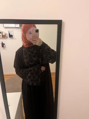 Abayaset - Så fin brun abayaset med glitterdetaljer. Abayasetet kommer med en underabaya och en öppen abaya. Helt ny med prislapp och oanvänd Storlek på underabaya: 140 cm Storlek på öppen abaya: 145 cm Totala bystmåtten på underabayan : 96 cm.