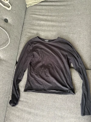 Svart långärmad topp från Monki - En enkel svart långärmad topp från Monki i mjuk bomull. Modellen har rund halsringning och en rak passform som funkar till det mesta. Perfekt basplagg att ha i garderoben.