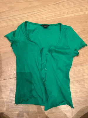 T-shirt - Säljer denna fina gröna t-shirt från Monki. Den är väldigt fin då man knäpper den framme. Köparen står för frakten💕