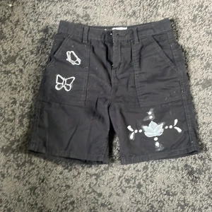 Svarta cargo shorts  - Svarta cargo shorts med fjärils design på. Handmålade. 