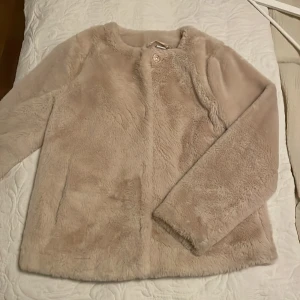 Jacka  - En riktigt snygg fuskpäls i mjukaste materialet. Den är perfekt, både under hösten och våren då den ej är fodrad. Sparsamt använd. 