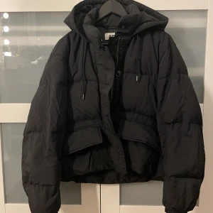Svart pufferjacket - Svart pufferjacket från UniQlo!! Så varm och perfekt till vintern!  Har en luva.  Ena knappen till vänstra fickan har gått av, se tredje bilden. Finns en innerficka med dragkedja  Inköpspris: ca 2000kr  