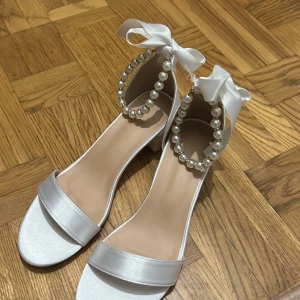 Klackar  - Helt oanvända vita klackar, säljer pga storlek för stor. Kan anvädas som bröllopsskor, studentskor, festskor m.m. Väldigt fina och sköna. 