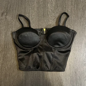 korset🖤 - en korsettliknande topp i blankt material med dragkedja i ryggen!