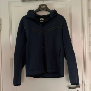 Nike Tech Blå - Säljer nu min Nike tech då slutat använda mig ut av den. Är i storlek M. Tröjan 9/10. Skriv gärna om yttligare frågor.