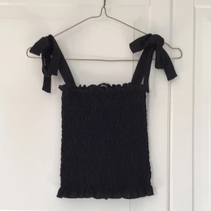 Svart rosett linne - Ett svart linne från Gina Tricot med rosetter på axlarna. Använt få gånger. Skriv till mig för fler bilder eller frågor😊