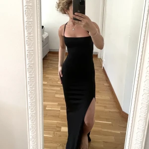 balklänning  - Svart balklänning i glittrigt tyg. Klänningen har öppen rygg med snörning och en snygg slits vid ena benet. Storleken går typ att justera då man kan spänna snörningen i ryggen. Finns flera liknande klänningar i min profil!