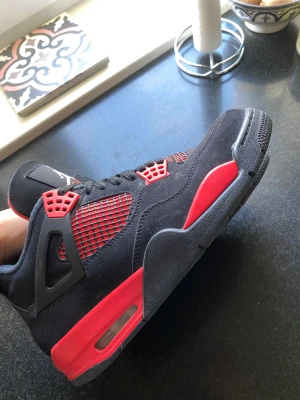 Jordan 4 Red Thunder strl 44 - Jordan 4 ”Red Thunder” i storlek 44.  Använda men i bra skick.  Köptes helt nya för över 5000 kr och säljs nu pga av jag behöver pengar till annat 