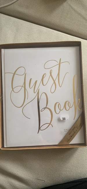 Gästbok, Guest Book - Säljer en gäst bok med guld text detalj som inte användes! Inte använd och ligger i original kartong. Väldigt fin och hård yta med blanka papper utan streck.   Nypris: 300kr Mitt pris: 200kr  Hämtas i Barkarbystaden!