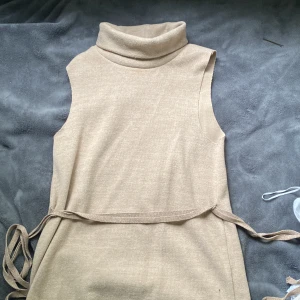 Stickat linne  - Super cool härlig stickad tröja utan armar och med polokrage. Har ett band som man kan knyta runt eller ta bort helt. I en Beige färg och i storlek S. Från zara perfekt i höst