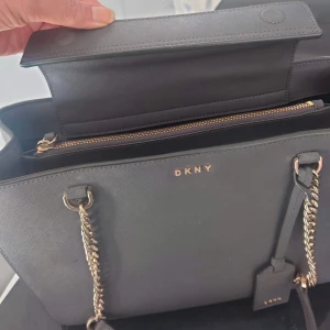 DKNY väska  - Jag säljer nu min gamla favvo väska från DKNY💖 super rymlig, får plats med dator osv, dustbag ingår. Jag köpte den på NK i Göteborg så den är äkta och i fint skick med äkta läder!!  Måtten är 34x23,5 🫶💖