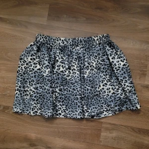 Leopardmönstrad kjol - En finare, uppiffande kjol i blå/vitt leopardmönster. Den är avslappande, vid och har ett resåband i midjan. Sitter ihop med en svart innekjol. Mycket skön att ha på sig.