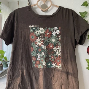 Graphic tee blommor brun  - Säljer min bruna t-shirt från Pull&bear med bruna, gröna, vita och orange blommor :) stl: S, men passar bra på XS också. Skriv om du har frågor✨