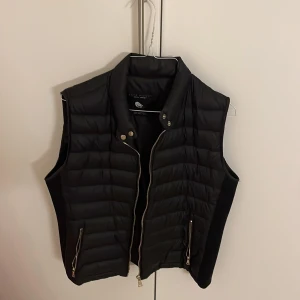Zara väst - Jätte snygg Zara väst som köptes för några år sen men som sällan använts. Sitter jättefint intill kroppen då den har som stretch material på sidan. Gulddetaljer. Liten i storlek. Skriv för fler bilder.