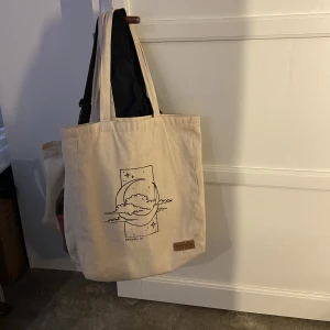 tygväska  - En super fin tygväska med tryck på! Köpt av ett uf företag som lagt ner. Använd lite men inget som syns. 