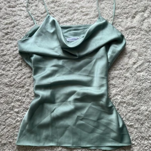 Turkos satin topp - Säljer en turkos satin topp, superskönt material och perfekt för fest eller till vardags. Den är köpt i en spansk secondhandbutik och i helt perfekt skick. Färgen är ljus turkos/ljusblå/grön och materialet är glansigt (satin) 