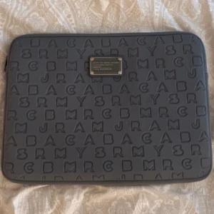 Marc Jacobs datorfodral  - Datorfodral från Marc Jacobs. Tror inte just denna modell säljs längre. En minimal rostfläck på metallmärket som knappt syns (se bild 2) annars är fodralet som nytt.  Mått: 35 • 25 cm 