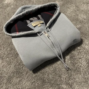 Burberry  Zip Hoodie   - Burberry Clarendon zip hoodie i mycket bra skick, använd fåtal gånger sen den köptes i England på burberry bicester village. Storlek är en XL men sitter som en L.  Hör av dig om du har frågor eller vill ha fler bilder.