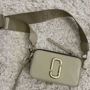Marc Jacobs snapshot väska - Säljer min Marc Jacobs snapshot väska i beige, då den inte kommer till användning längre. Nypris: 4299kr Kvitto skickas på begär, har ej kvar varken lådan eller dustbagen.