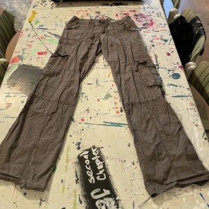 Bruna cargobyxor  - Utsvänga cargobyxor. Midjemått, raktöver: 39cm. Innerlårsmått: 82 cm.