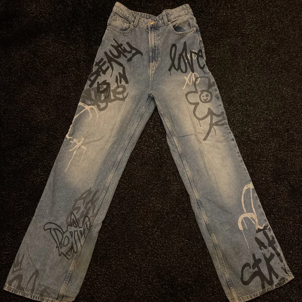 Högmidjade jeans med fake-klotter på. Använda fåtalet gånger men varit ganska långa på mig så kan ha blivit lite missfärgade längst ner på benen-därför avdraget pris. Annars är de jättesköna, sitter bra över röven och fått många komplimanger för byxorna!. Jeans & Byxor.