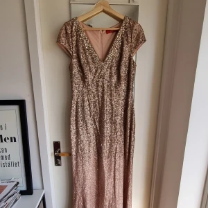 Glittrig klänning i rosé, med paljett - Helt otroligt fin klänning (mycket finare än på bilderna) som sitter så fint på kroppen. Passar perfekt för nyår, födelsedag, gala eller bara för att du är en Queen helt enkelt. Fin v-ringning och dragkedja bak. Använd endast en gång. Storlek 12/40/L.