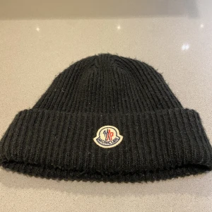 Moncler mössa - Tjena, säljer nu min svarta moncler mössa då den inte kommer till någon användning! Skick: 7/10 lite nopprig, färg: svart, size: onesize. För mer info eller bilder skicka ett meddelande!