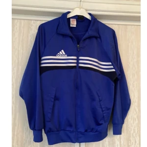 Blå Adidas tröja sweater jacka dragkedja st M/L - Blå adidas träningsjacka. I utmärkt skick! Mått: 56 cm armhåla-armhåla. 65 cm längd uppifrån och ned.   Finns att hämta i Stockholm! Hör av dig om du har någon fundering och titta gärna in mina andra annonser.