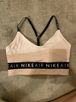 Sport-bh - Säljer denna sportbh från Nike i ljusrosa färg med svarta detaljer! Borttagna ilägg - men går att lägga i egna!  
