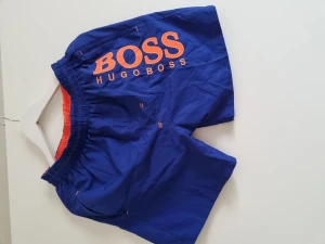 Badshorts - Blå badshorts med dragkedjor i fickorna. Relativt oanvända.