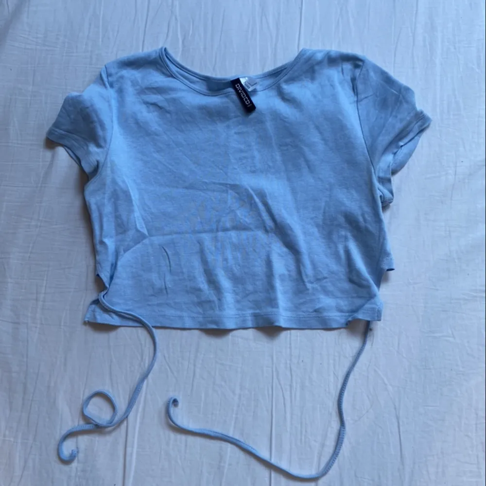 Snygg T-shirt med knytning baktill🩵 Den är väldigt liten till storleken. . Toppar.