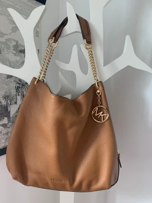 Axelväska från Michael Kors - Axelväska från Michael Kors Mycket sparsamt använd så i mycket fint skick. Det enda som går att anmärka på är några små rispor/märken från kattungeklor men det syns bara om man tittar nära. Orginallåda och tillhörande påse medföljer