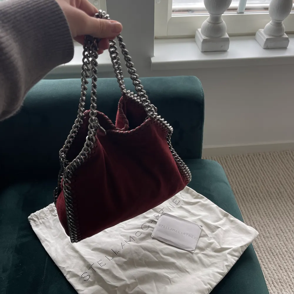 Säljer min gulliga vinröda Falabella Mini (mellanstora)🫶🏽💕 Den har ett hål i innertyget och är lite missfärgad på insidan + att kedjorna rostat lite, därav priset (säljs för 10 ny). Väskan är självklart äkta och du får med både dustbag och ”äkthetsbevis”🫶🏽💕. Väskor.