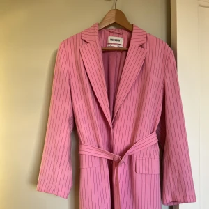 Kavaj från Weekday - Kritstrecksrandig rosa kavaj i oversizemodell med tillhörande bälte i midjan strl 38 (passar 36-38)  Används för sällan  Ej skråmor eller förändringar i material