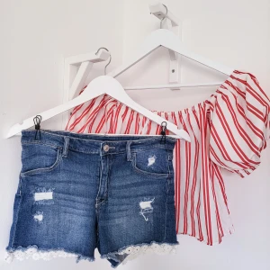 BikBok Offshoulder topp & Jeans Shorts - Denna röda randiga off shoulder topp är i storlek 34 (passar även som 36) och är i mycket bra skick. Tröjan har en bekväm passform och är mjuk och skön att bära. Shortsen är i storlek 170. Denna outfit är perfekt för sommardagar.🌻