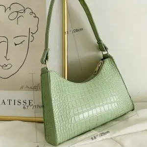 En grön handväska i ”ormskinn” med en guld dragkedja. Hör av er vid frågor och vid snabb affär kan priset sänkas:)