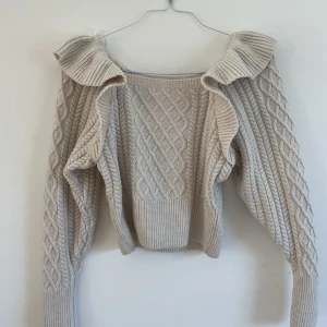 H&M tröja med volang  - Kabelstickad tröja med volang från H&M (Varit i garderoben en lång tid därav ser den mörk/stel ut!) Ordinarie pris: 299kr