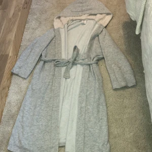Morgonrock  - En grå morgonrock med två fickor och en fluffig luva, Ärmarna är lite korta.