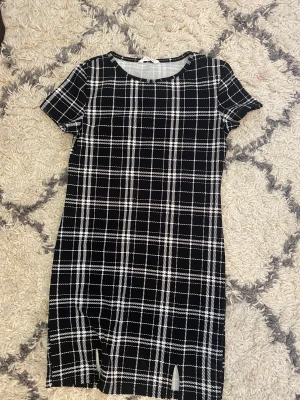 Klänning  - En rutig svart vit klänning med två slitsar i slutet av klänningen.  