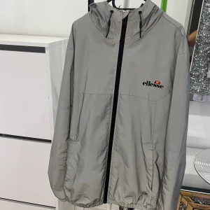 Ellesse Cesanet Jacka - Denna regnjacka köptes från zalando för cirka 1år sedan, skick 9/10. Jackan är byggd med reflex så när man tar blir med blixt (flash) så lyser hela jackan upp. Pris går att diskutera!