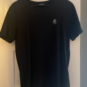 Tiger of Sweden T-shirt - Tiger of Sweden T-shirt i fint skick med vitt peace tecken fingrar embroderad på bröstet. Bak vid nacken finns även ett litet Tiger of Sweden märke i svart väldigt subtilt