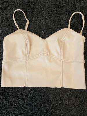 Skinntopp - Skinntopp toppskick då den aldrig har kommit till användning. Dragkedja på sidan. Strl s