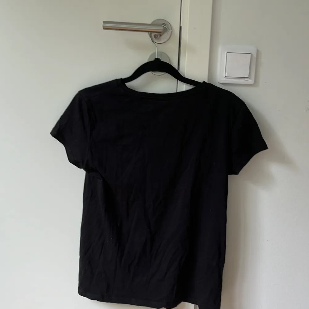 En svart t-shirt som självklart stryks innan utskick . T-shirts.